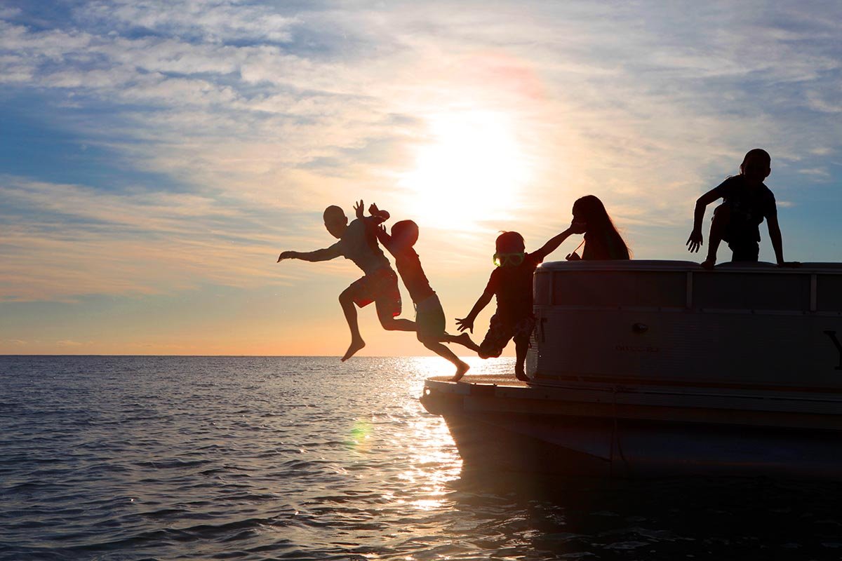 Kids jumping off a boat at sunset